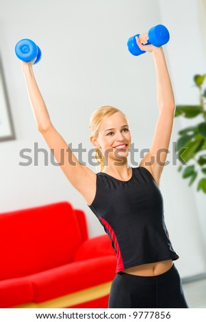 Young woman doing fitness exercises with dumbbells at home