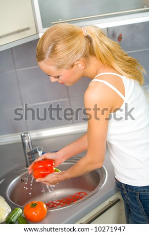 Young woman washing vegetables at domestic kitchen