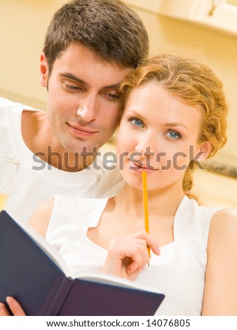 Young happy couple planning with notebook together at home