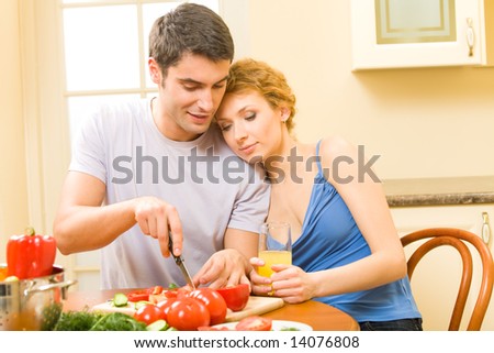 Young happy couple making salad at home together