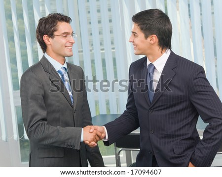 Two businesspeople cheering by handshake at office
