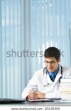 Happy young doctor or student writing at office
