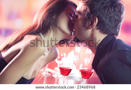 Couple kissing on romantic date or celebrating together at restaurant