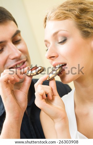 Young amorous couple eating cookies together at home