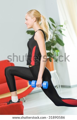 Young happy woman doing exercises with dumbbells at home