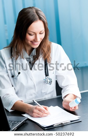 Happy female doctor with pill and clipboard at office