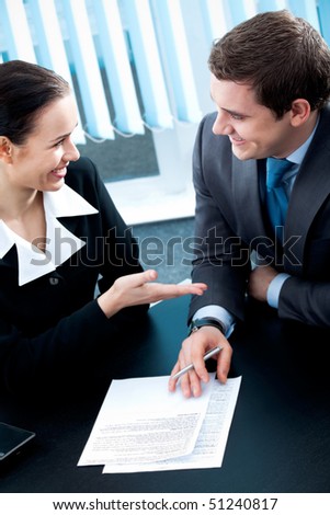 Businesspeople or business person and client, with document at office