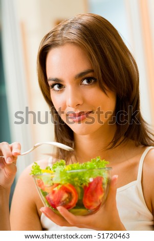 Young happy smiling woman with salad at home