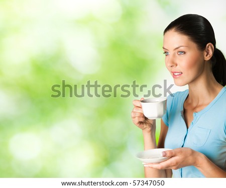 Young happy smiling woman drinking coffee, outdoors. You can use left part for slogan, big text or banner.