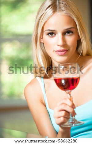 Young happy smiling woman with glass of red wine