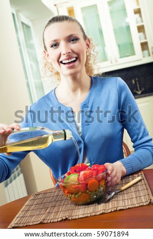 Young happy woman making salad at home