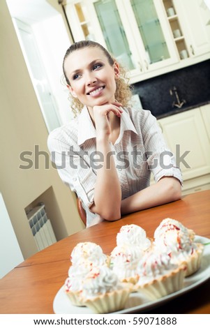Young happy woman with plate of cakes at home. Focus on woman.