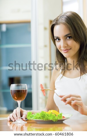 Young smiling woman with salad and redwine at home