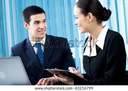 Two happy businesspeople working together at office. Focus on woman.