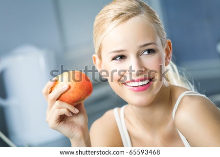 Portrait of young happy smiling woman with apple at home