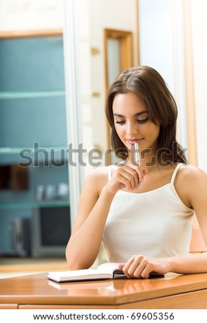 Young happy smiling thinking woman with organizer, at home