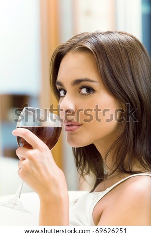 Portrait of young woman with glass of red wine, at home