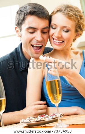 Young happy couple with champagne and cakes at home