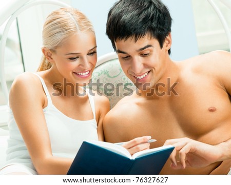 Young happy smiling couple with notebook or organizer at home