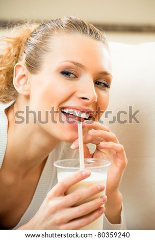 Young happy smiling woman drinking milk at home
