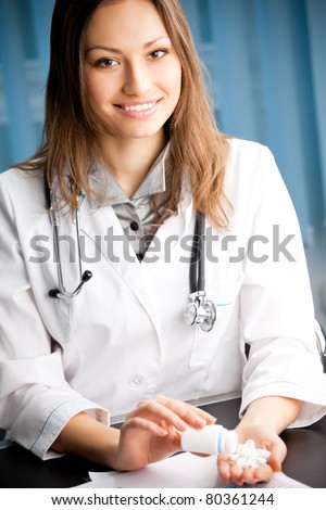 Happy smiling female young doctor with pill at office