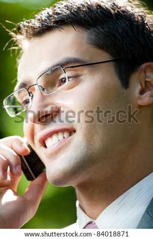 Portrait of young happy smiling businessman working with cellphone, outdoors