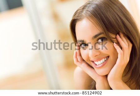 Portrait of young happy smiling beautiful woman, at home. You can use left part as copyspase for slogan or text.