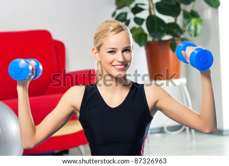 Portrait of young happy smiling woman in sportswear, doing fitness exercise with dumbbells, at home