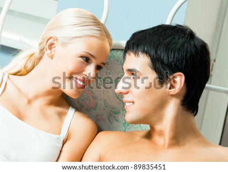Portrait of young happy smiling amorous couple looking at each other, at bedroom