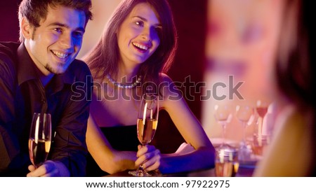 Three young people with champagne glasses at restaurant