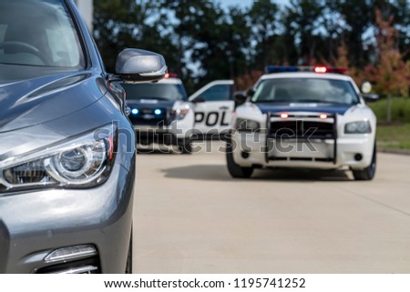 Two police vehicles stop a sedan on a routine traffic stop