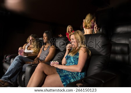 A group of people watching a movie showing emotion as a couple makes out in the back