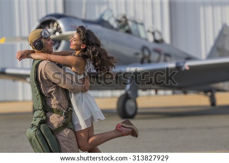 A brunette model in vintage clothing with a pilot and a WW II aircraft