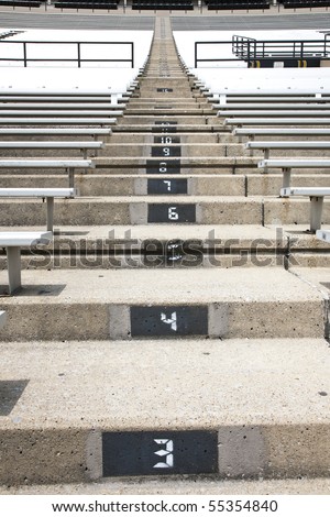 A picture of some empty bleacher seating in rows, taken in a modern school sports stadium facility.
