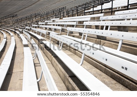 A picture of some empty bleacher seating in rows, taken in a modern school sports stadium facility.