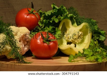Vegetable set of white pepper, two red tomatoes, salad leafs, parsley and dill branches laid pretty on the table