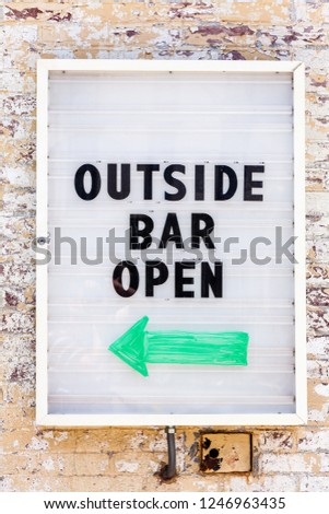 Sign on the wall reading: Outside Bar Open
