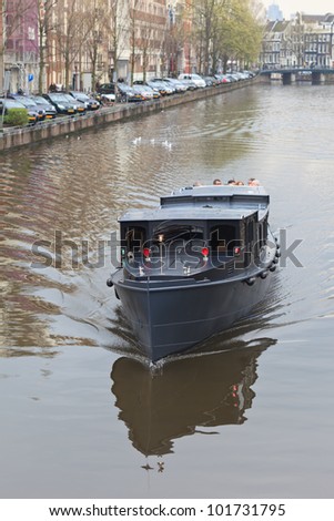 AMSTERDAM, NETHERLANDS - APR 20: Tourist boat cruises on canal in Amsterdam on April 20, 2012. Almost 20 percent of all canal cruise boats are now electrically powered