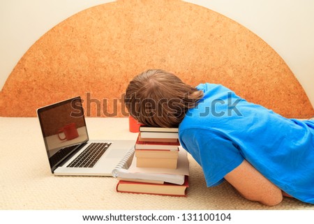 Man sleeps in front of his laptop on pile of books