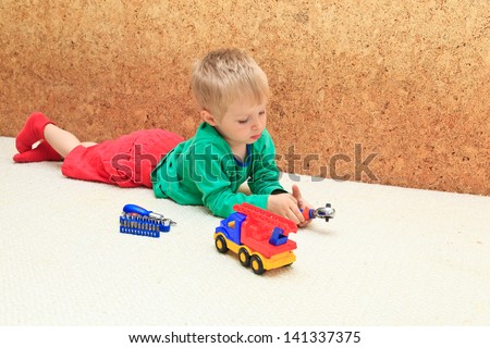 Little cute boy repairing a plastic toy truck, early learning concept