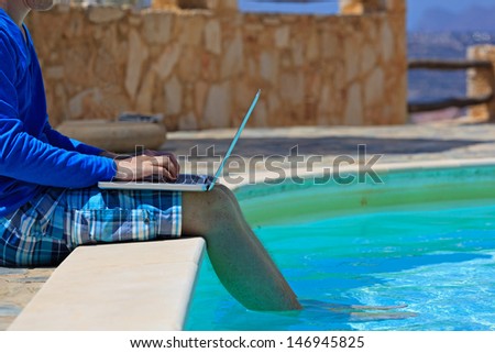 working on laptop at the pool, work on holiday concept