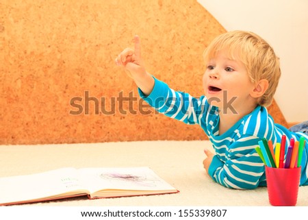 portrait of cute little boy raising hand to give answer, early learning