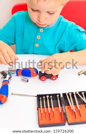 Little boy repairing toy train, early learning concept
