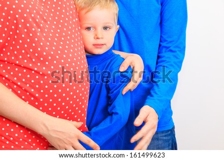 happy expecting family: father and son embracing mother tummy