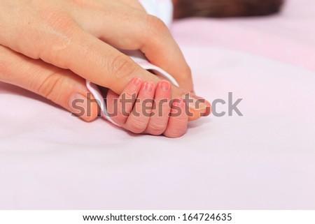 Newborn baby is held by the hand the parent. Care and support.