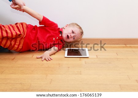 Parent pulling child from touch pad. Computer Addiction