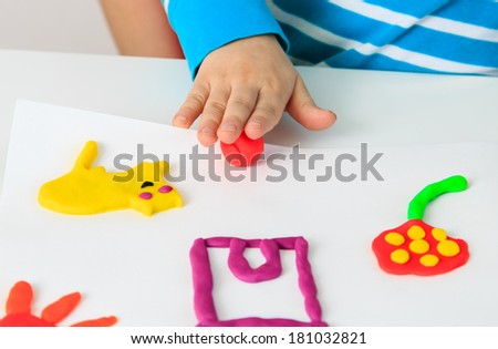 Child playing with colorful clay molding different shapes - closeup on hands