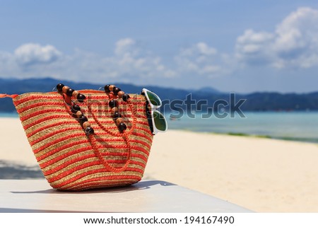 bag and sun glasses on tropical beach, vacation concept