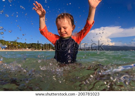 little boy playing with water on tropical beach