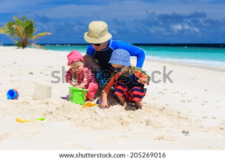Father and kids making sand castle at tropical sand beach